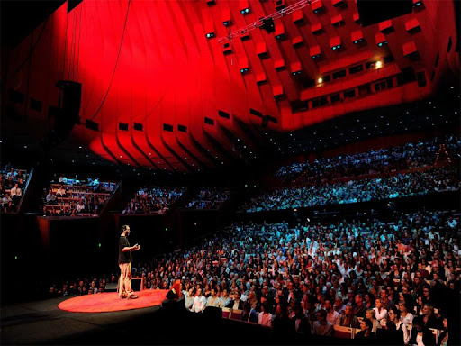 Ted speaker facing the audience on stage speaking to people